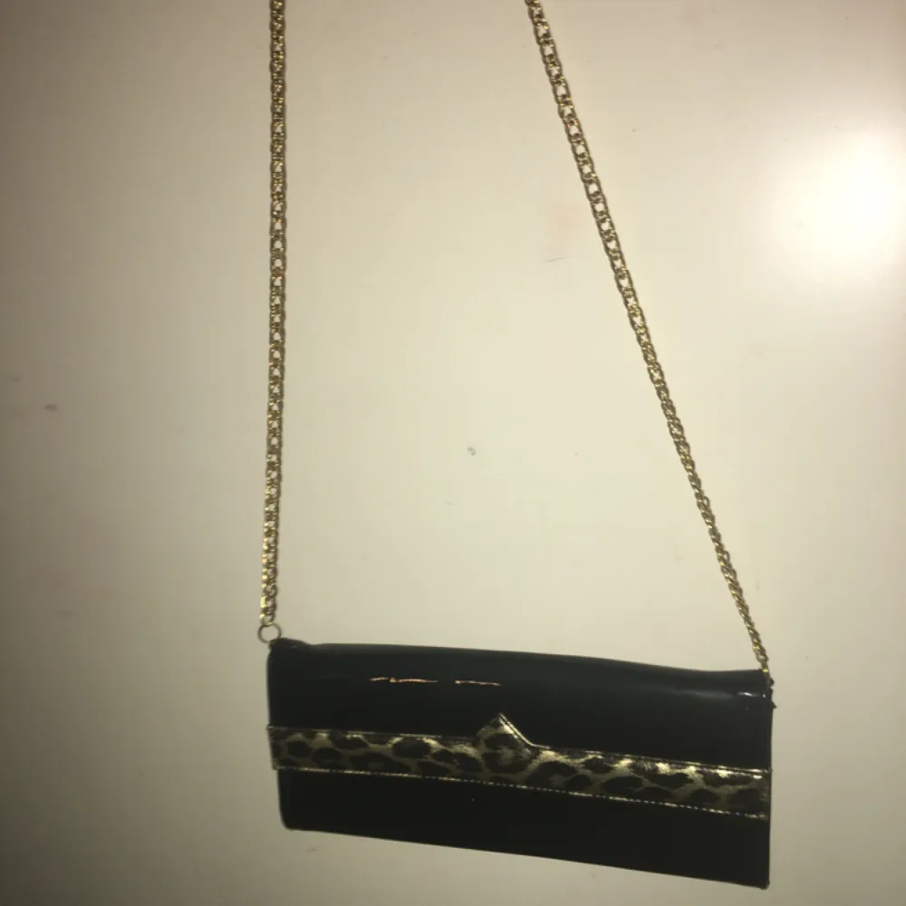 Jättecool, svart handväska med guldigt band och leopard-detalj.. Väskor.