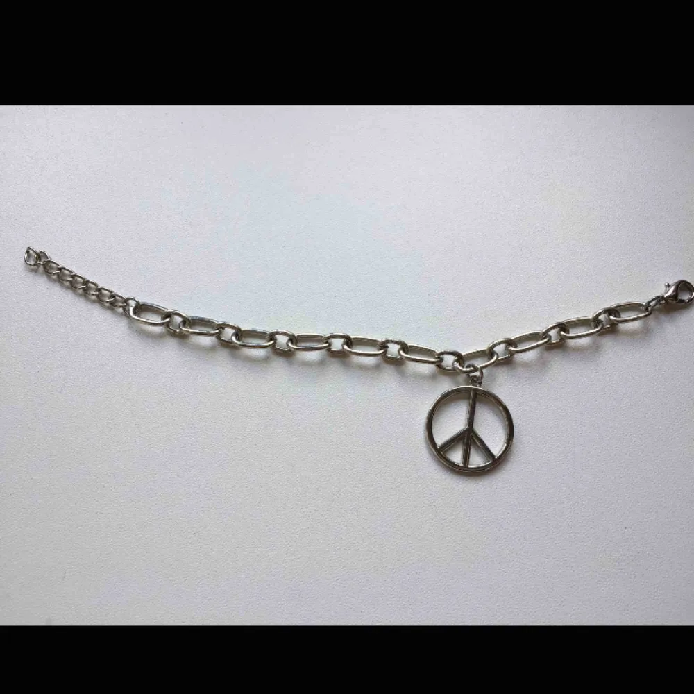 Silverfärgad charmsarmband med peace symbol. Ca. 21cm lång.  Frakt med Postnord är 9kr.. Accessoarer.
