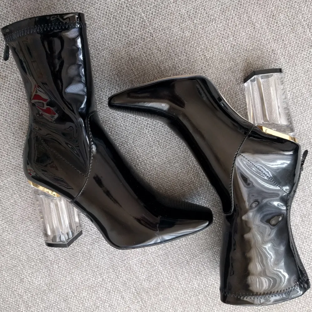Svarta boots i glansigt lack/PVC fuskläder. Med dragkedja och perspex klack. Klackhöjd ca 5 cm, fyrkantig tå. Supertrendiga! Endast använda en gång inomhus. De passar en vanlig storlek 37. Hämtas/möts upp i Stockholm för köp eller 49 kr frakt. . Skor.