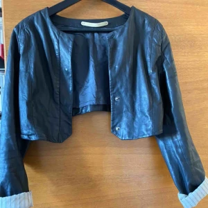  - skinnjacka/kavaj i svart whyred, mkt kort ovan midjan  skick saknar knapp och väl använd. skinnintakt behöver tvättas..?   köparen betalar frakt