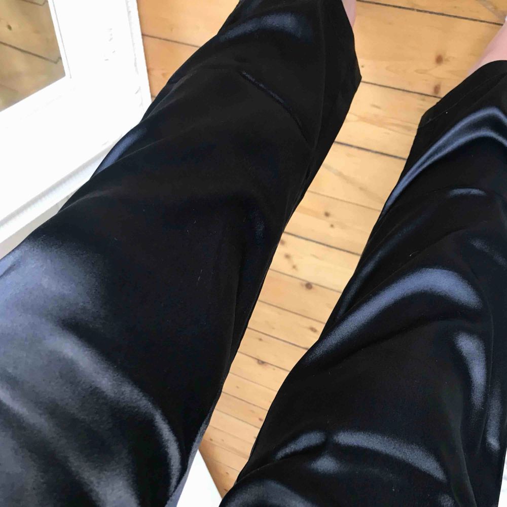 NYA kostymbyxor i svart glansigt material.  Byxorna har resår i midjan & dragkedja vilket gör att de anpassar sig efter din kroppstyp.  Jättesnygga både till festligare tillfällen & vardags. . Jeans & Byxor.