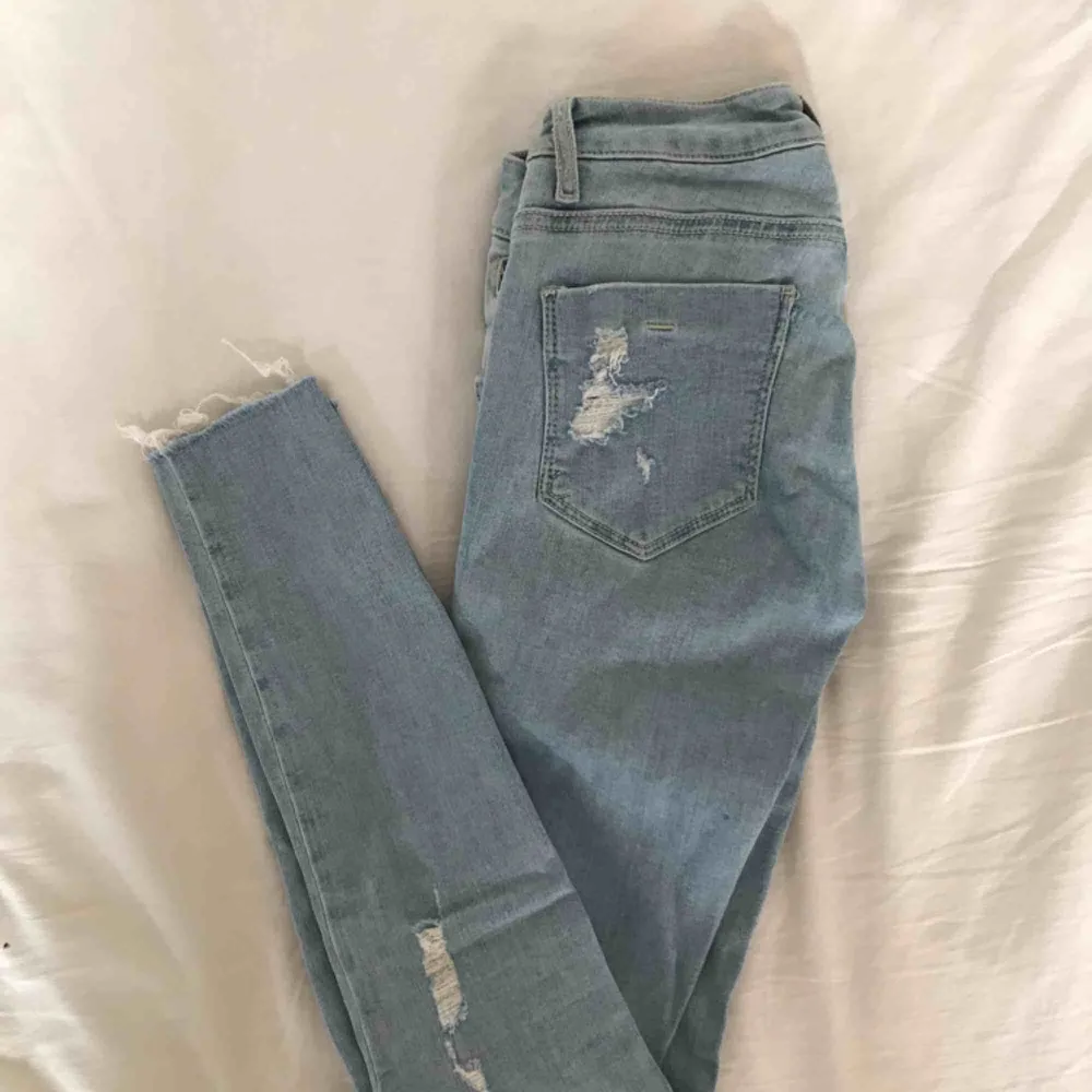 Ljusblåa jeans från bikbok med hål på bl.a knäna och ena fickan. Jeansen har även en dragkedja vid fickan som en snygg detalj. Modellen är mycket lågmidjad🤪fraktar men fraktkostnad tillkommer . Jeans & Byxor.