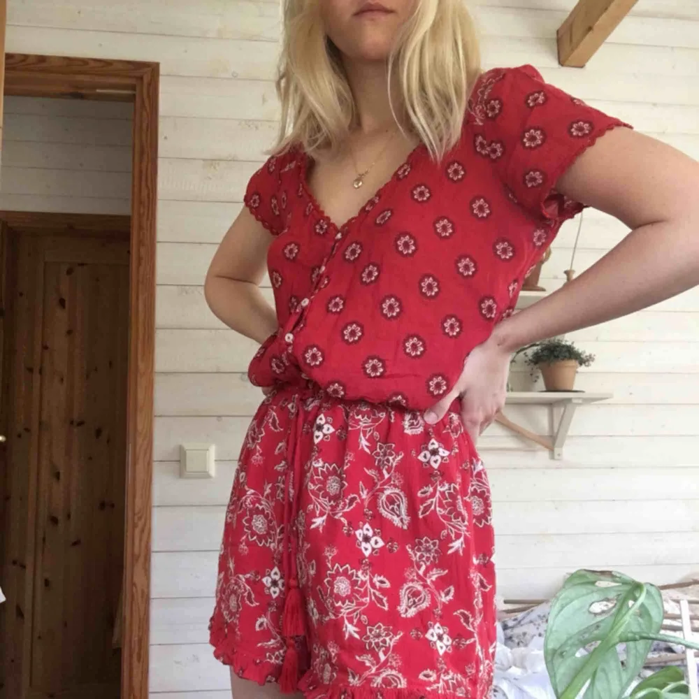 Röd blommig jumpsuit från hollister, knappt använd . Klänningar.