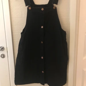 Dungaree klänning  - Svart klänning med spännen och fickor i strl S från MONKI 