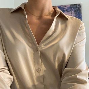 Skjorta - Skjorta i glansigt material, aldrig använd endast tvättad! Har en liten fläck från ett klistermärke (?) på ena sidan som är ca 6 mm stort, syns på sista bilden, har inte försökt ta bort det 🤍                   Kolla gärna in mina andra annonser! 