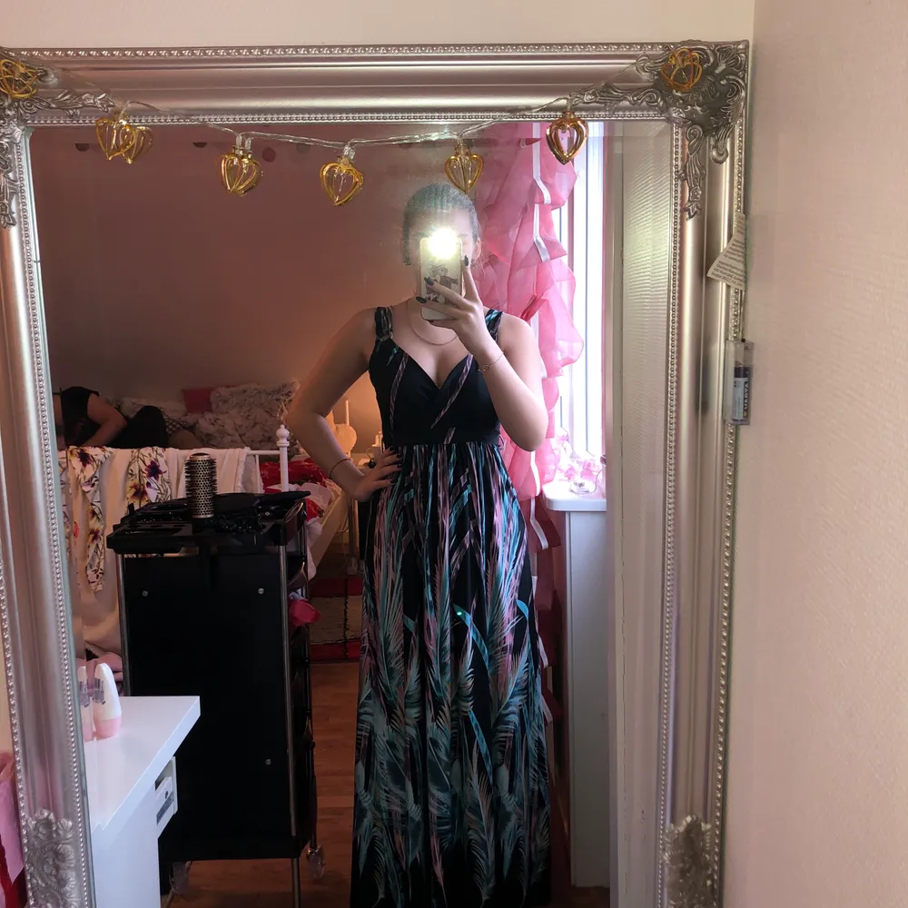 Jag säljer en lång svart klänning med lite rosa och blåa i. Jag är 165cm lång. (priset kan diskuteras). Klänningar.