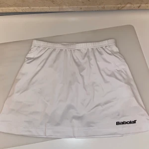 Vit tenniskjol - Intressekoll på denna vita tenniskjol från babolat! Shorts inuti. Barnstorlek 12-14, passar XS-S. Stretch i hela kjolen. Kan skicka fler bilder. Lägg ett bud från 100kr! Säljer endast vid bra bud. Fraktkostnad tillkommer. Ledande bud: 115kr
