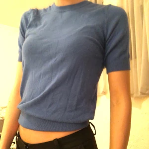 Stickad tröja från Zara - En finstickad blå t-shirt från zara. Guldiga knappar i ryggen.