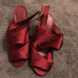 Röda skor  - Klackskor i något silke liknade material,använd en gång, har ett silver/diamant smycket vid sidan. Är från NA-KD , i storlek 35 ( kan mötas upp) 