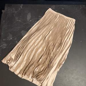 Guldig kjol i mjukt silkesliknande material med glittrigt resår i midjan