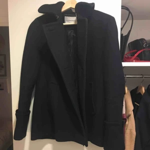 Kort kappa i ull - En kort kappa i ull från Viktor & Rolfs kollektion för H&M. Den är i väldigt bra skick, den enda anmärkningen är att knapparna är borttagna. Den hålls dock stängd ändå om man använder haken högst upp vid kragen, eller om man syr på nya knappar.  