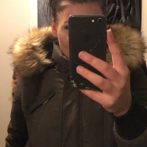 Snygg vinterjacka! - Militärgrön jacka vadderad och varm. Bra skick och knappt använd pälsen är i väldigt fint skick den med. Läder vid armbågarna samt luvan.