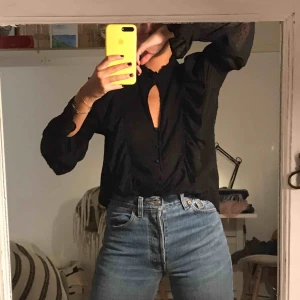  - Oanvänd svart blus med volanger och knapp i halsen. Köpt på bikbok. Frakt tillkommer 