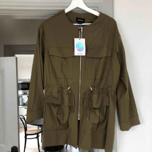  - Jacka från Monki i militärgrön färg. Storlek xs men passar även S och M. Funkar lika bra inne till byxor som jacka ute. Helt ny med lappar kvar. Säljer likadan i svart. 