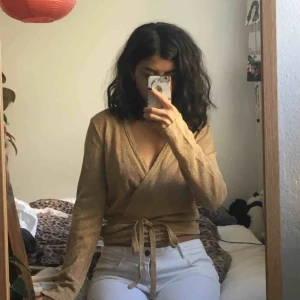  - Fin guldglittrig stickad omlottopp. Lagom varm och sitter jättefint. Perfekt för hösten och vintern!