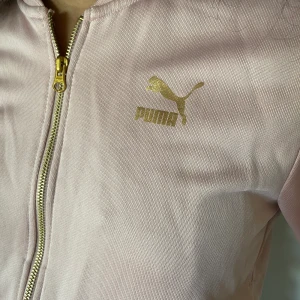Croppad kofta från puma - Ljusrosa med guldetaljer och vit rand på ärmarna, använd en gång, från kollektionen KENZAxPUMA