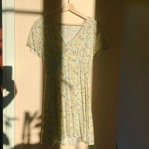 Gul blommig klänning  - Jättesöt klänning med gula, rosa och blå blommor. Sitter väldigt bra och är väldigt smickrande. 