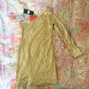  - Oanvänd guldig enarmad paljettklänning från Nelly, märke club L