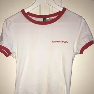 En vit T-shirt med röda ärmar och krage från H&M med tema från Stranger Things🔦. Sparsamt använd och i bra skick