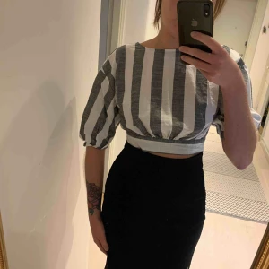  - Kort blus i linneliknande material. Öppen rygg