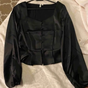 Blus från Nelly  - Säljer en blus jag köpt här på plick som kommer från Nelly. Den är superfin i ett glansigt satin material. Bilden är tagen från tjejen jag köpte den ifråns plick men egen bild kan tas såklart. Frakter eller möts upp i Falun. Hund finns i hemmet. Obs en knapp fattas.