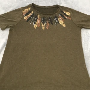 T-shirt med detaljer  -  T-shirt med vackra detaljer, för tjej ålder 12-15 Kan mötas upp annars står köparen för frakten. Stockholm!