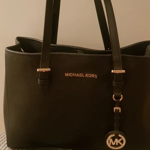  MICHAEL KORS Jet Set Travel MD.  - Äkta MK väska.  I fint skick, knappt använd. Den har 2 stora fack + ett fack i mitten med dragkedja. En liten sidoficka med dragkedja och 2 små öppna fickor. Kommer med ett avtagbart och justerbar axelrem. Mått: B×H×D 30×22×12 cm. Köparen står för frakten