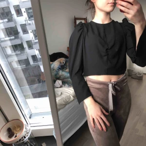  - En svart blus med ”ruffle” armar. Helt oanvänd. 