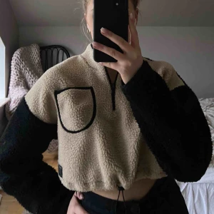  - Trendig beige/svart Teddy sweatshirt med ficka, dragkedja och går även att ”spänna” i midjan. Kortare i modellen. Använd 2 gånger. Nypris- 600 kr. Fraktkostnad 30 kr (köpare står för frakten)