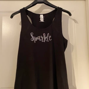 Svart träningslinne ”sparkle” - Svart träningslinne med texten ”sparkle” i rhinestones/strass. Finns i Västerås, annars står köparen för frakt.