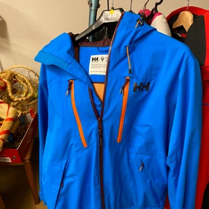 Helly hansen regnjacka, M - En fin lysande blå helly hansen jacka som står emot regn till 100% i storlek M, inga fläckar eller hål så den är i princip i nyskick, nypris=1200