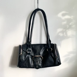 läderväska med spänne - intressekoll på frän läderväska med stor spännedetalj samt dragkedjor. obs! spännet är inte det riktiga låset, utan endast för utseende. väskan stängs med magnetlås. skriv för intresse! frakt tillkommer eller möts upp i sthlm<3