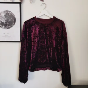 Tröja i krossat sammet - Lila tröja i krossat sammet med mudd längst ned. Jättefint skick, jag har endast använt den ett fåtal gånger. Resårbandet har trasslat till sig lite, men det går nog att rätta till. Därav priset. Gratis frakt!