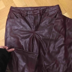  - MÖRKLILA skinnimitation byxor!! Lite smått utsvängda nertill. Mindre defekter visas på sista två bilderna. Jag är ca 164 cm å de är precis så att de inte är för långa. 😻