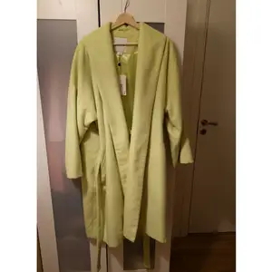 En grön/gul neonfärgad kappa från Monki. Har testat den i affären men aldrig använt. Prislappen finns kvar. Kan skicka fler bilder om det behövs :)