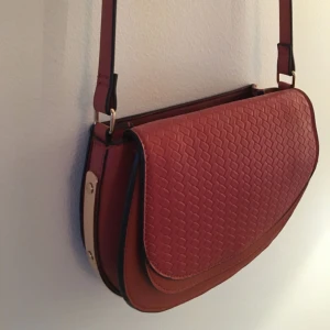  - Mörkröd axelremsväska✨ i skinnimitation med gulddetaljer från HM. Knappt använd och i mycket fint skick! Frakt tillkommer.