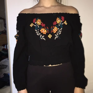  - Fin svart blus från H&M. Nästan helt oanvänd. Mönster fram och på ärmarna, blusen kan bäras både upp- och nerdragen på axlarna. Strl 34 men passar en 36a.
