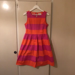  - Ljuvlig cocktail klänning i orange/rosa ränder. Den har en mindre svart fläck på sig, som jag är övertygad om att den går att få bort. Lär kanske räcka med bara en vanlig tvätt.  Den blir väldigt tight i midjan och puffig kjol, vilket är svårt att visa i kameran. Lite stretchig vilket gör att det är större sannolikhet för en bra fit.  Frakt tillkommer