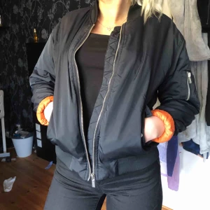  - Svart bomber jacka från Junkyard med 4 fickor, Dock ett hål i ena framficka som går att laga. Orange på insidan 