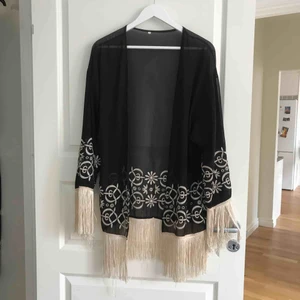  - Svart lite genomskinlig ”kimono” med beigea detaljer och fransar. Köpt på nätet, kommer ej ihåg märke.