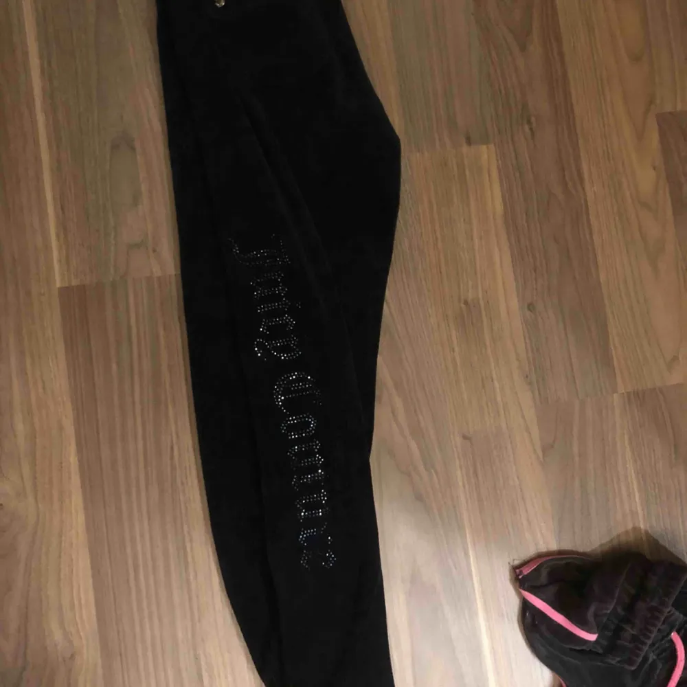 Svarta mjukisbyxor från juicy couture med svart glittrig text längst benet. Jeans & Byxor.