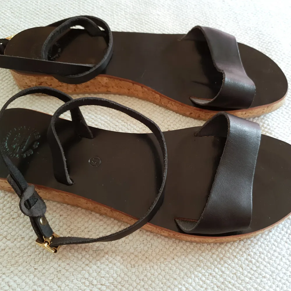 Superfina svarta sandaler med spänne runt vristen och korkliknande sula. Använda endast en gång. Säljer pga av för liten storlek. Strl 39/40. Nypris 2600. Skor.