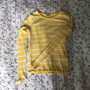  - Tight randig långärmad i gult och vitt. Använd väldigt få gånger. Fina små volanger vid ärmarna och i slutet på tröjan. Frakt tillkommer.
