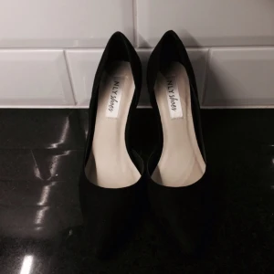  - Aldrig använda skor i svart fake suede med spetsig tå från Nelly. Storlek 38 men liten i storleken. Klackhöjd 9,5 cm.👩🏽👩🏼👩🏿 ink. Frakt