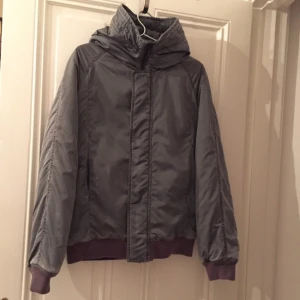  - Bomberjacka från Whyred i grått med luva. Herrstorlek 46 vilket motsvarar S-M för dam. Använd en gång. 