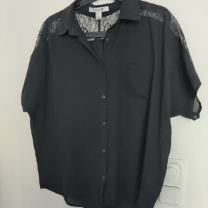 Blus/skjorta Forever21 - Svart blus/skjorta med spets på ryggen från Forever21. Sparsamt använd, strl L. Skickar spårbart med PostNord, köparen står för frakten