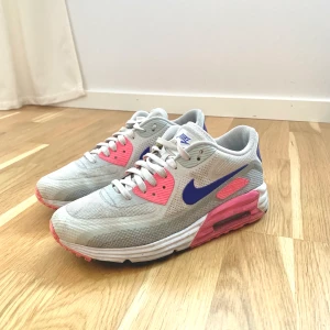 Nike Air Max-skor/ stl. 40/ fint skick - Nike Air Max-skor i fint använt skick. Skorna har färgen ljusgrå/silver med rosa och blålila detaljer. Mycket bekväma, ger foten god stabilitet. Storlek 40. Nypris 1 300 kronor. (Har inte tvättat av skorna vid bildtillfället). 