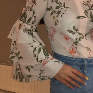 Blommig topp - Blommig topp med trumpetarmar. St S på lappen men passar även M.  Skicka ett DM eller skriv i kommentarsfältet 🌸