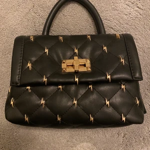 Liten väska med blixtrar  - En liten handväska från asos använd en gång. Säljer för 150kr (+frakt)❤️ Den har ett långt band och ett kort 😍