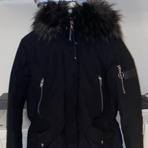 Rockandblue jacka - Varm vinterjacka i svart färg med grå/svart fuskpäls runt luvan. I nyskick då den kommit till väldigt lite användning. Normal i storleken samt så är den justerbar i midjan för bättre passform. Finns att hämta i Kungsängen men kan även mötas upp i Stockholm området. Priset kan självklart diskuteras